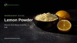 Pale cream-yellow lemon powder in a dark bowl with whole and halved lemons on dark stone