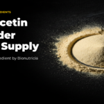 Liposomal quercetin powder shown as a mound of pale yellow powder on a dark surface
