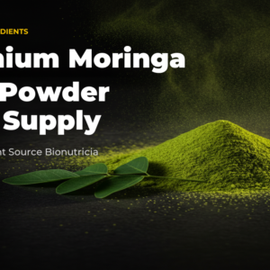 Moringa leaf powder shown as a mound of green powder with fresh leaflets on a dark surface