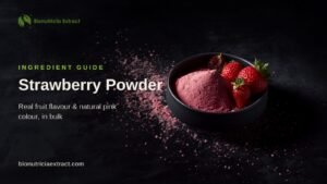 Rose-pink strawberry powder in a dark bowl with fresh strawberries on dark stone